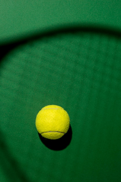 Flat lay of tennis ball with racket shadow