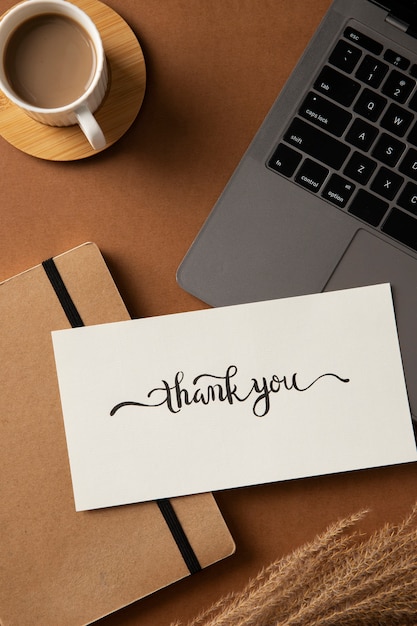 Free photo flat lay thank you note and laptop