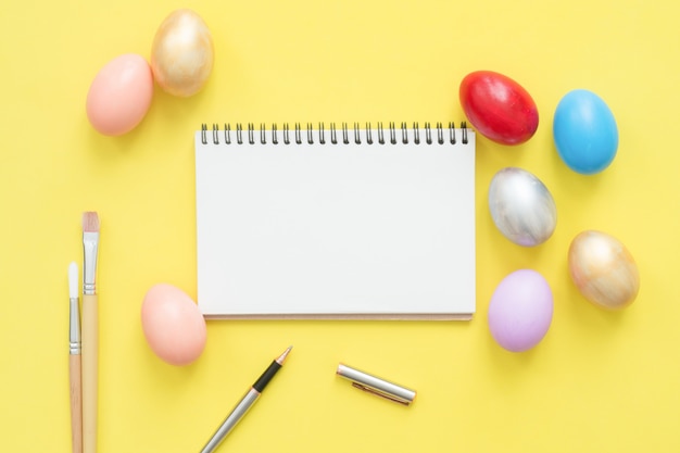 Flat lay top view colorful easter egg painted in pastel colors composition and mock up blank notebook