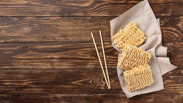 Flat lay uncooked noodles and chopsticks with copy space