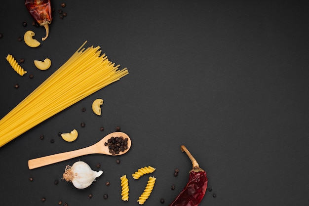 Free photo flat lay uncooked pasta with wooden spoon ingredients and copy space