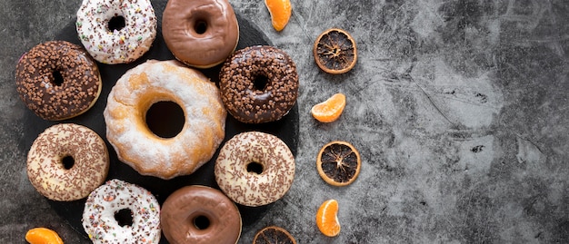 Flat lay of variety of doughnuts with dried citrus and copy space