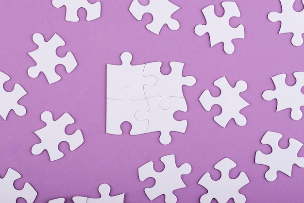 Free photo flat lay white puzzle pieces and purple background