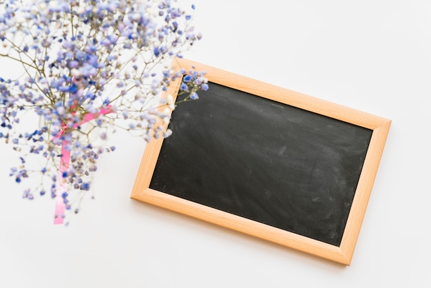 Free photo flat lay with small chalkboard and flowers