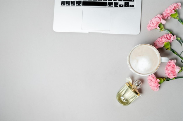 Flat lay woman office desk Workspace with laptop pink carnation stationery on white table Top view