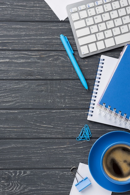 Flat lay of wooden desk with coffee cup and keyboard