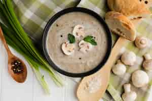 Free photo flat lay wooden spoon and mushroom bisque with bread and mushrooms