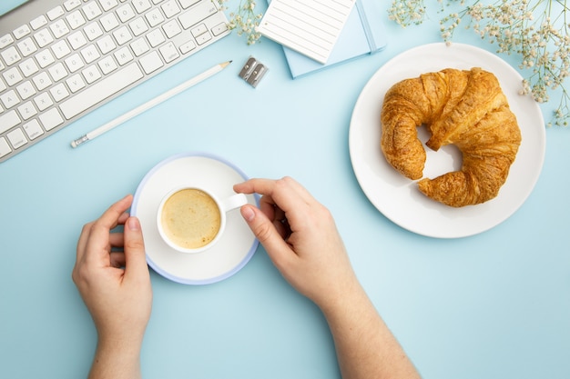 Flat lay workplace arrangement on blue background with breakfast meal