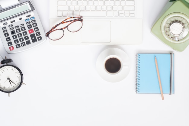 Flat lay of workspace desk with white laptop, stationery and cup of coffee