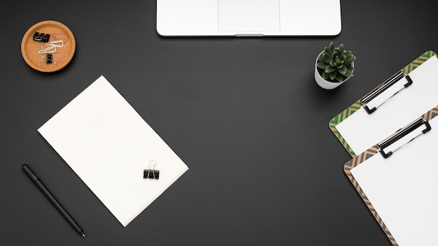 Flat lay of workstation with notepads and succulent plant