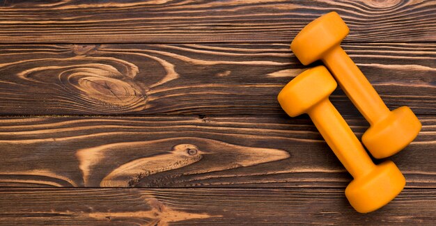 Flat lay of yellow weights on wooden background and copy space