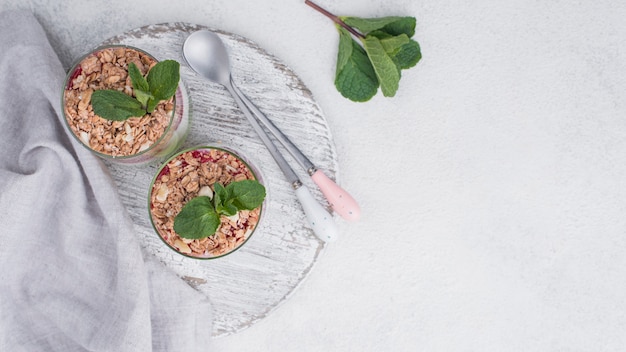 Flat lay of yogurt glasses with cereal and copy space