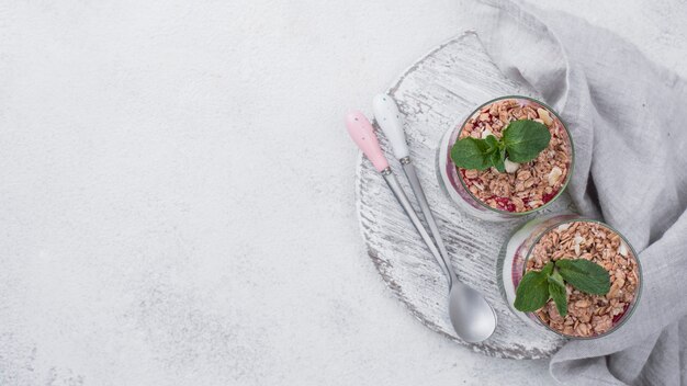 Flat lay of yogurt glasses with cereal and mint