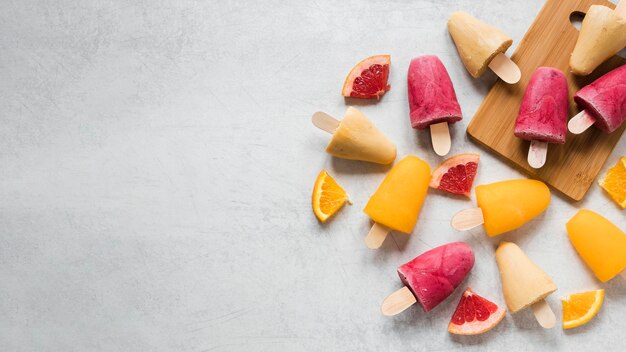 Flat lay of yummy popsicles with fruits and copy space