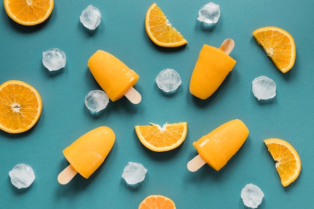 Free photo flat lay of yummy popsicles with ice and orange