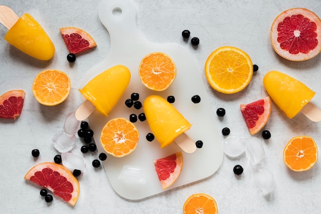 Free Photo flat lay of yummy red grapefruit flavored popsicles with orange and blueberries