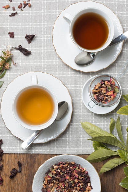 Flavored tea cups with dried tea herbs on wooden table cloth