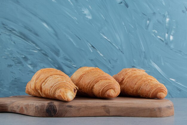 Flavorful croissant on board , on the marble background. High quality photo