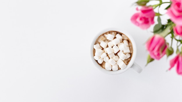 Free photo flay lay of marshmallow cup with roses and copy space