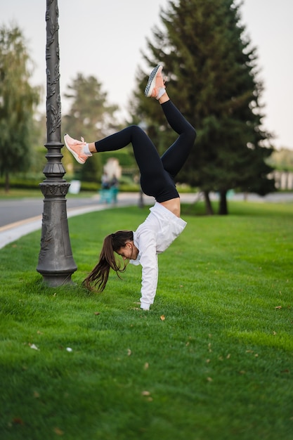 Flexible gymnast. Attractive skinny woman doing a backbend while showing a somersault. Outside