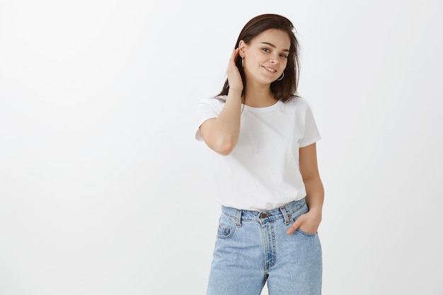 flirty young woman posing against white wall