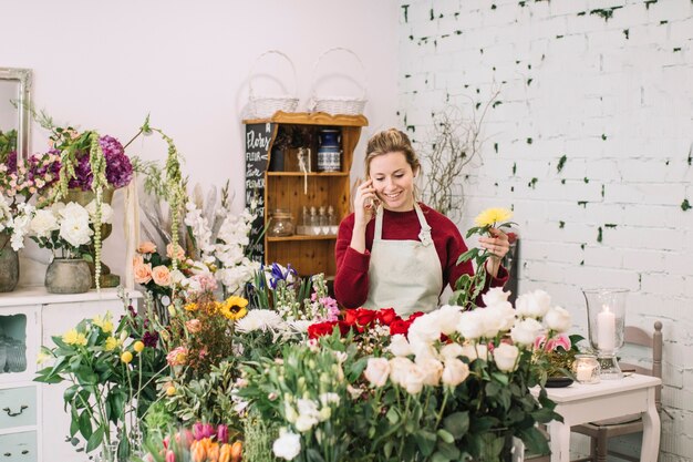 Florist speaking on smartphone and picking flowers