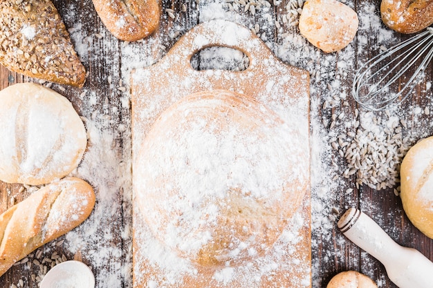 Flour over the chopping board and variety of breads on the table