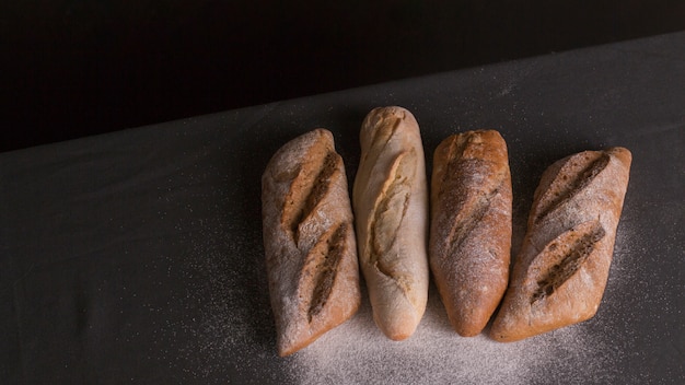 Free photo flour dusted on baked bread over black background