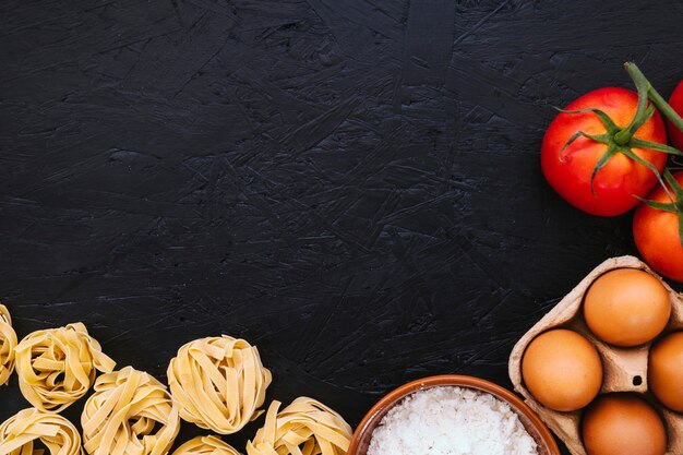 Flour and eggs near pasta and tomatoes