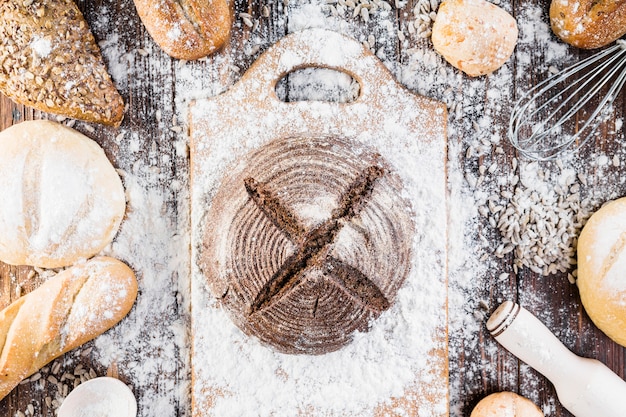 Free photo flour spreads over the different types of bread loaves on the wooden table