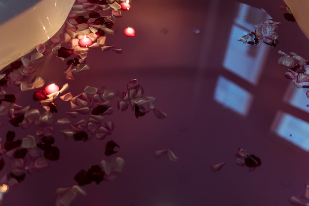 Free Photo flower petals on water near burning candles in spa tub 