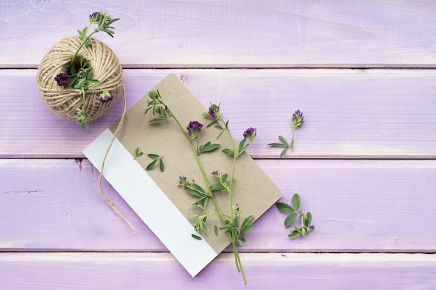 Free photo flower twigs on closed notebook with spool of string on purple wooden backdrop