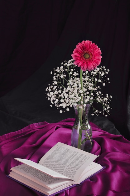 Free Photo flower with bloom twigs in vase near volume and violet textile in darkness