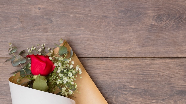 Free photo flowers bouquet in pack paper on wooden table