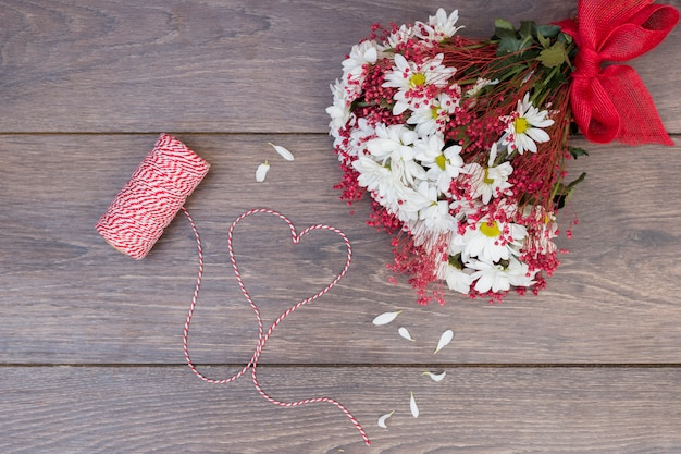 Flowers bouquet with heart from rope on wooden table