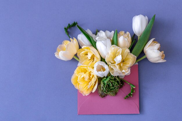 Flowers in an envelope on a colored background flat lay