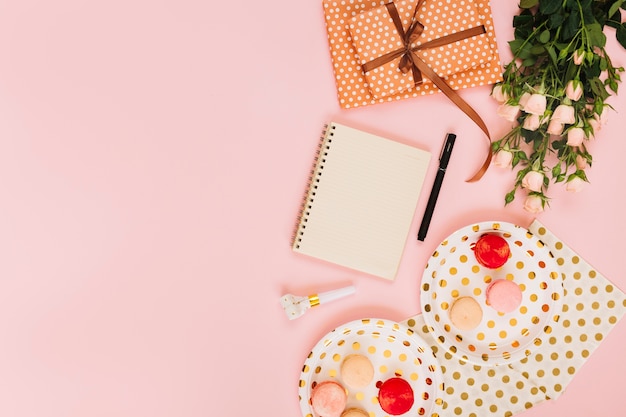 Flowers and gift near notebook and macaroons