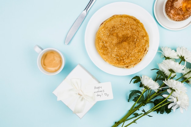 Flowers near present with tag and plates with crepes