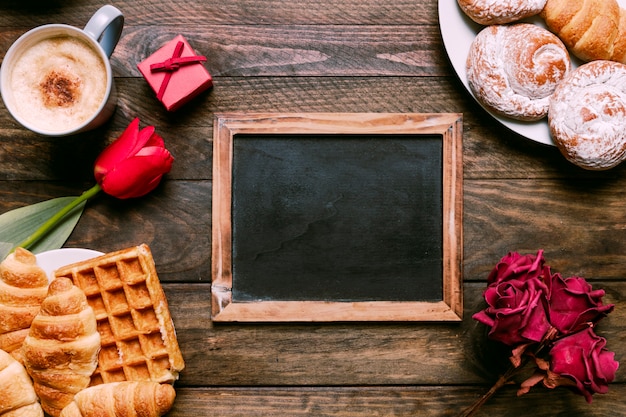 Flowers, photo frame, bakery on plates, gift box and cup of drink