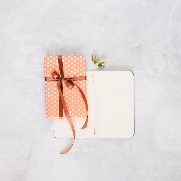 Flowers and present near empty notebook