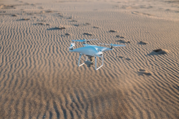 Free photo flying drone landing on sand at beach