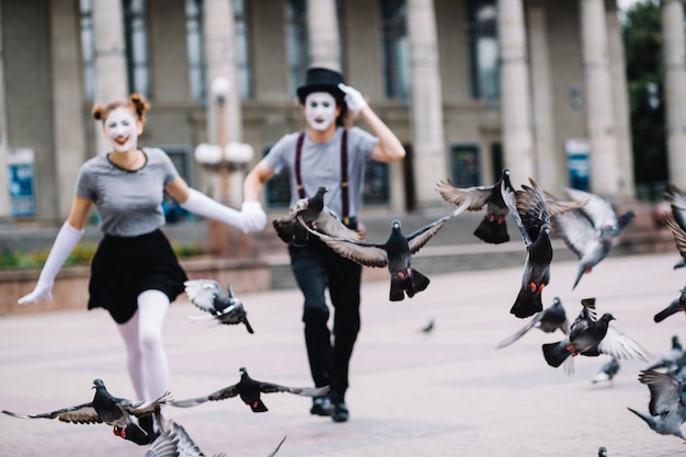 Free photo flying pigeons near running mime couple