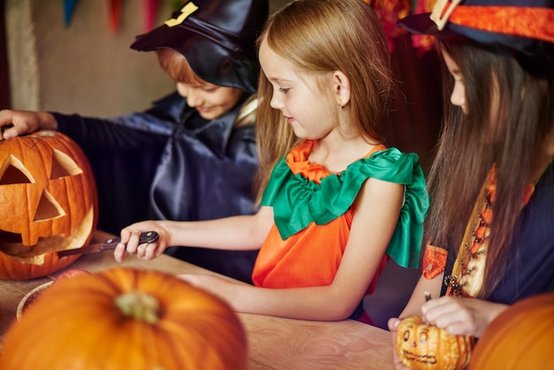 Focus children carving some shapes on the pumpkin