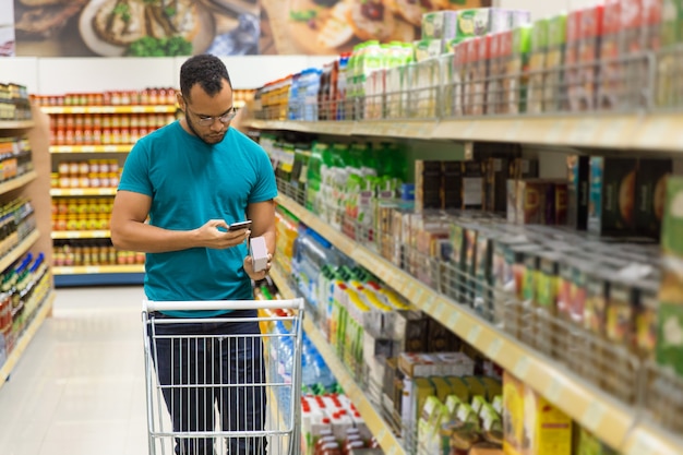 Focused African American man reading shopping list on smartphone