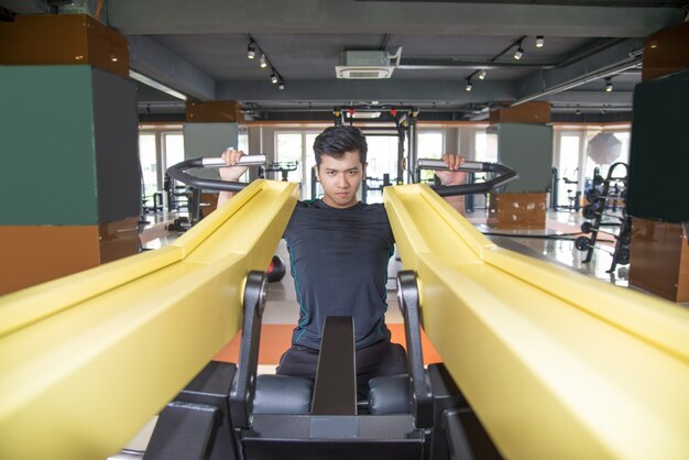 Focused Asian man training on exercise machine