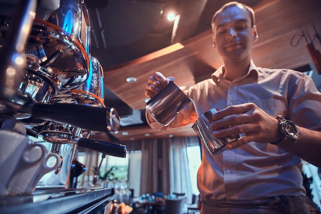 Free photo focused barista is prepairing coffee for customers using new shiny coffee maker.