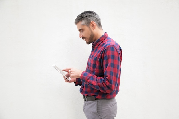 Focused bearded man using digital tablet