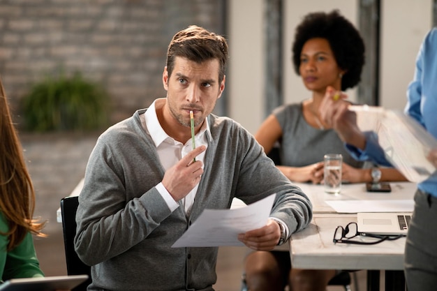 Focused businessman listening a presentation while being in board room with his colleagues