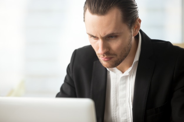 Focused businessman looking on laptop screen