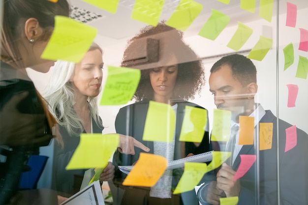 Free photo focused businesspeople reading documents and examining information. successful concentrated employers in suits meeting in office room and studying reports. teamwork, business and management concept